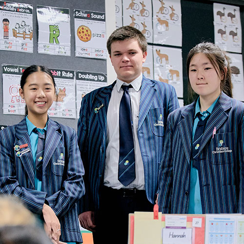 Three Secondary Students standing in front of Prep students at the classroom