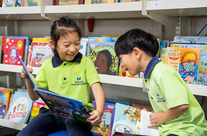Primary students reading at the library wearing their School houses uniforms